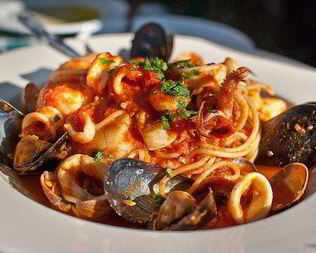Паста с морепродуктами, зеленью и чесноком в томатном соусе